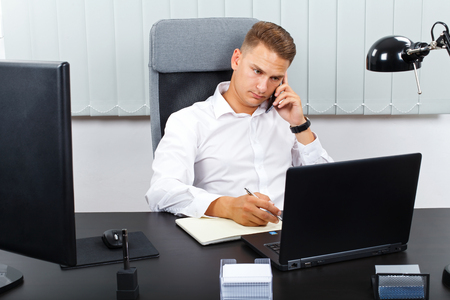 Photo of a young confident businessman talking on the mobile phoneの写真素材