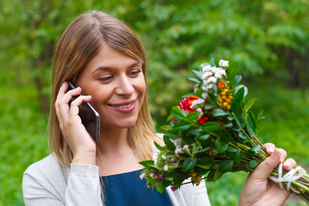 Portrait of a beautiful young woman holding a bouquet of flowersの写真素材