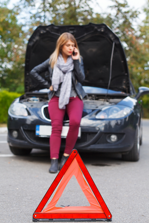Picture of a helpless young woman on the road with her car broken