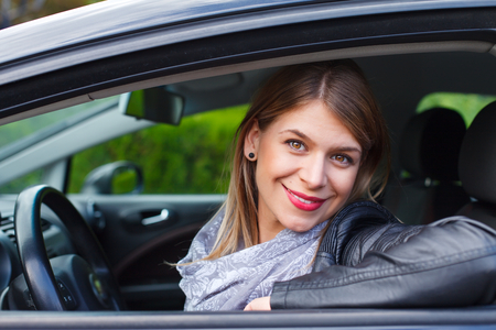 Portrait of a beautiful young woman in her new carの写真素材