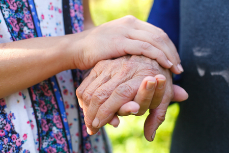 Close up picture of a senior woman holding her granddaughter's handsの写真素材