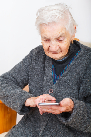 Picture of an old woman holding a cellphone in her handsの写真素材