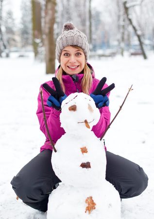 Picture of a young girl playing with a little snowmanの写真素材