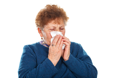 Picture of an elderly woman blowing her nose - isolated backgroundの写真素材