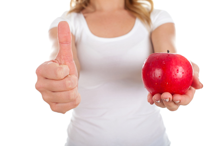 Close up photo of a woman holding a fresh apple and showing thumbs upの写真素材