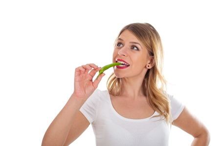 Picture of a beautiful girl eating a hot paprikaの写真素材