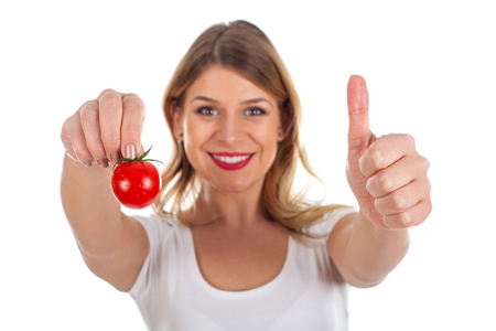 Picture of a beautiful young woman holding a fresh cherry tomatoの写真素材