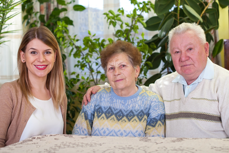 Picture of an elderly couple with their happy caretaker at home