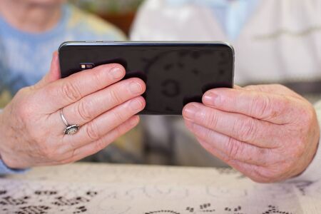 Close up picture of a senior couple's hands holding a smartphoneの写真素材