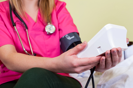Close up picture of a young carer holding an electronic blod pressure measurerの写真素材