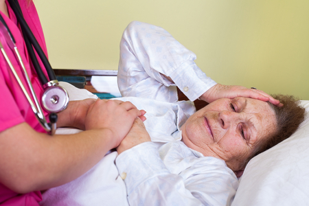Picture of a bedridden old woman having a headacheの写真素材