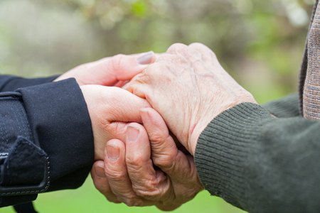 Close up picture of a young woman's hands holding an elderly female's handsの写真素材