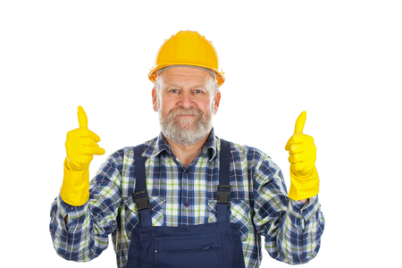 Picture of an elderly plumber wearing yellow helmet and gloves, showing thumbs upの写真素材