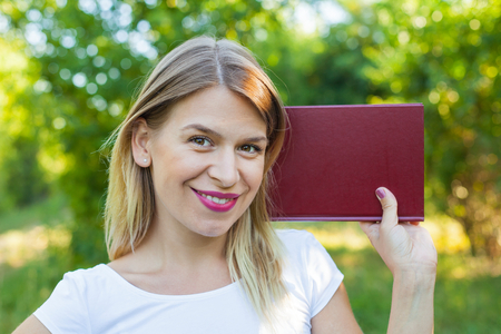 Picture of beautiful female student holding a notebook, posing outdoorの写真素材