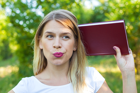 Picture of beautiful female student holding a notebook, posing outdoorの写真素材