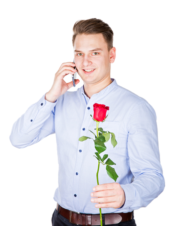 Portrait of a handsome guy with red rose in his hand having a phone call with his girlfriendの写真素材