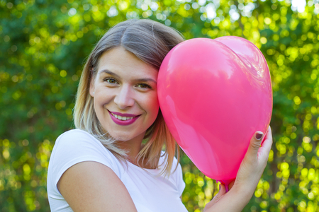 Picture of a sexy caucasian woman posing with a heart shaped balloon outdoor on summertimeの写真素材