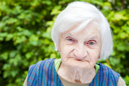 Portrait of an aged woman sitting outdoor in the garden on summertimeの写真素材