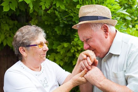 Senior man kissing his wife's hands, elderly couple in love outdoorの写真素材