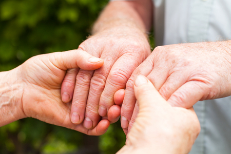 Close up picture of elderly couple holding hands outdoorの写真素材