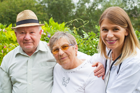 Friendly medical doctor with elderly couple smiling at the camera outdoorの写真素材