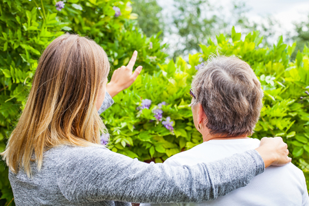 Picture of a senior lady with her friendly caregiver in the park, back viewの写真素材