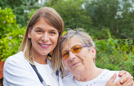 Disabled elderly woman in the park with young female medical doctorの写真素材