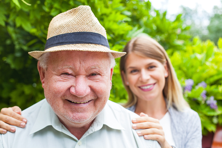 Smiling elderly man with beautiful young granddaughter posing in the parkの写真素材