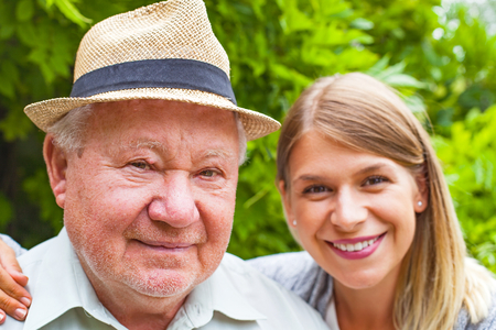 Smiling elderly man with beautiful young granddaughter posing in the parkの写真素材