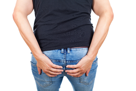 Young man having viral diarrhea, holding his bottom on isolated, back viewの写真素材