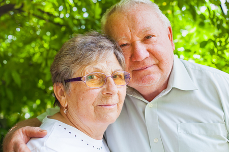 Happy elderly couple in love hugging in the park on a summer dayの写真素材