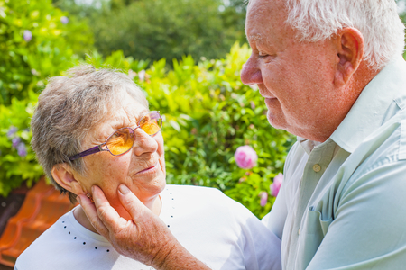 Happy elderly couple in love hugging in the park on a summer dayの写真素材