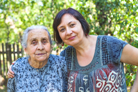 Middle aged woman posing with her sick old mother in the gardenの写真素材