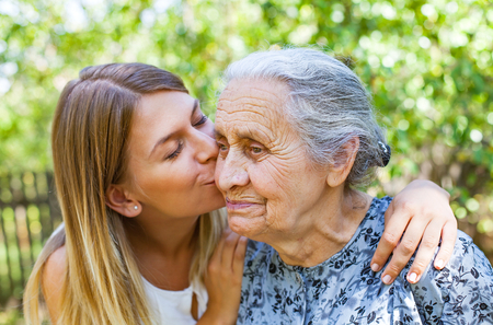 Young woman kissing her old grandmother in the parkの写真素材
