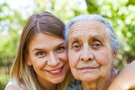 Close up picture of senior disabled woman with loving granddaughter in the gardenの写真素材