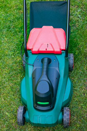 Close up modern lawn mower on the grass in the backyardの写真素材