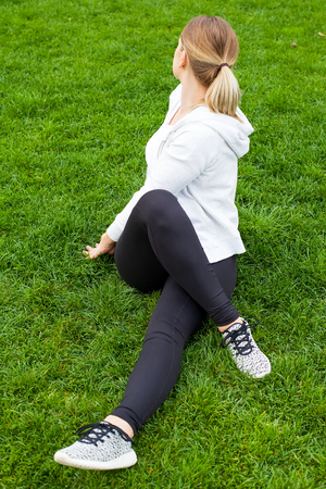 Young woman sitting on the green grass doing yoga exercisesの写真素材