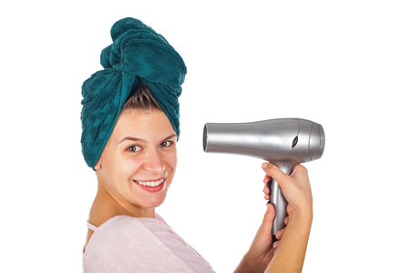 Smiling young woman with bath towel on head holding a hair dryer - isolated backgroundの写真素材