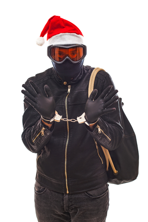 Arrested thief wearing mask and santa claus cap with handcuffs on isolated backgroundの写真素材