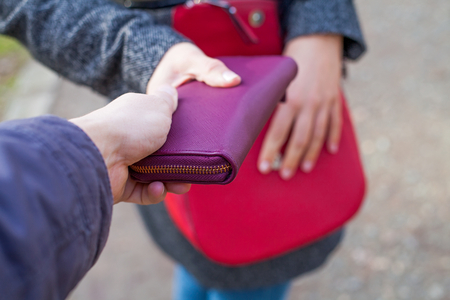 Close up picture of woman holding her red bag while a thief trying to steal from herの写真素材