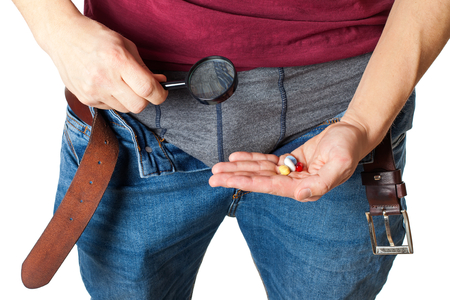 Close up picture of man's crotch with unzipped jeans holding potency pills and enlarged viewerの写真素材