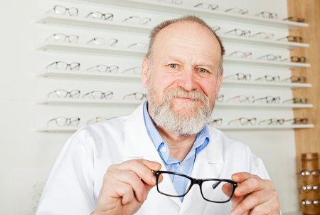 Confident mature ophthalmologist wearing white uniform in optical store