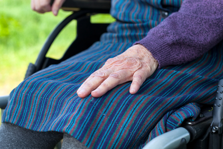 Close up picture of elderly woman's hands, sitting in a wheelchair outdoorの写真素材