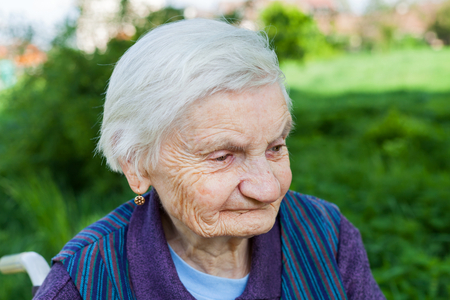 Close up portrait of smiling elderly woman suffering from dementia disease, outdoorの写真素材