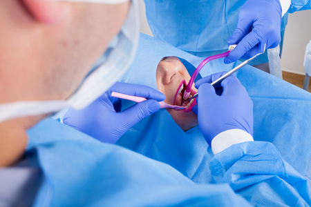 Dental surgery. Dentist and assistant working. Young female patient's oral cavityの写真素材