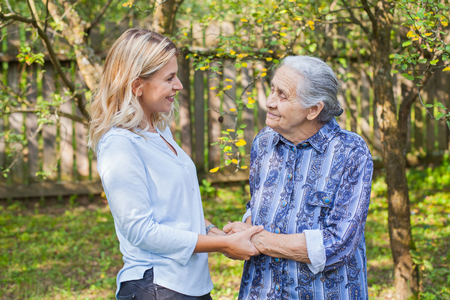 Friendly caregiver walking with old lady in the garden - Medical careの写真素材