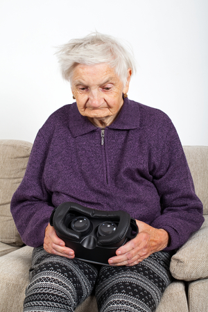 Elderly retired woman experiencing virtual reality video with headsetの写真素材