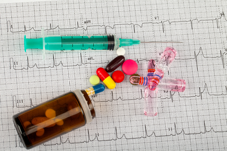 Close up picture of medical drugs and a syringe on an electrocardiogram formの写真素材