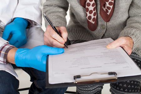 A senior woman's hand signing a documentの写真素材