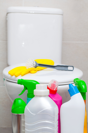 Colorful bathroom cleaning products and yellow rubber gloves, white lavatory pan in the backgroundの写真素材